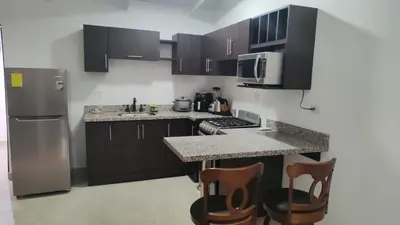 a kitchen with a refrigerator and a counter with chairs at Villas jaco costa rica in Jacó