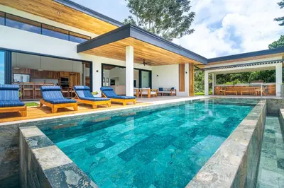 a swimming pool with blue chairs and a house at NEW! Luxury-4 Suites-Private pool-Ocean views in Coronado