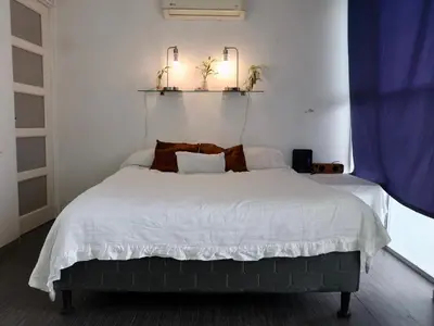 a bedroom with a large bed with two lights on the wall at Amá in Puerto Limón