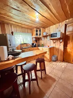 a kitchen with a wooden table and some stools at Ecos del Poás vista a la montaña in Dulce Nombre