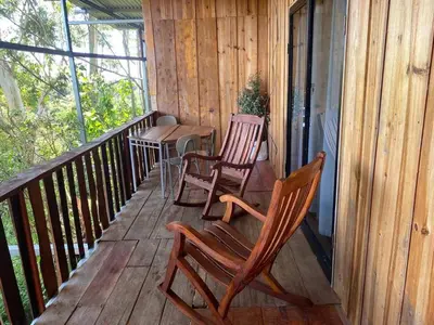 two chairs and a table on the porch of a cabin at Ecos del Poás vista a la montaña in Dulce Nombre