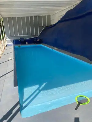 a blue swimming pool with a yellow hose next to it at Ecos del Poás vista a la montaña in Dulce Nombre