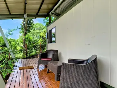 a room with chairs and a table on a wooden deck at Casa Abierta Playa Juquillal 2 habitaciones in Santa Cruz