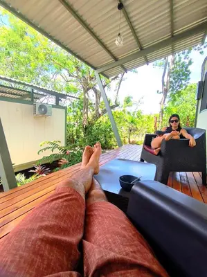 a person laying on a deck with their feet on a table at Casa Abierta Playa Juquillal 2 habitaciones in Santa Cruz