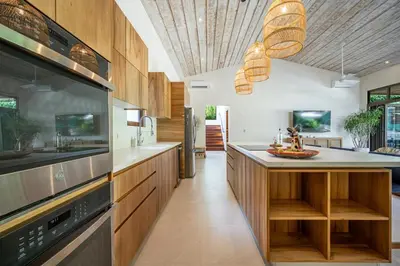 a kitchen with wooden cabinets and a large appliance at Casa Cheetah Gated Luxury Villa with Guest House in Tamarindo