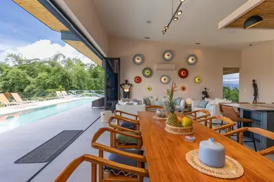 a dining room with a table and a swimming pool at Villa Buddha Belly OceanMountain top views in Quepos