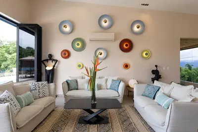 a living room with two couches and a wall with clocks at Villa Buddha Belly OceanMountain top views in Quepos