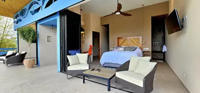 a bedroom with a bed and two chairs and a table at Villa Buddha Belly OceanMountain top views in Quepos
