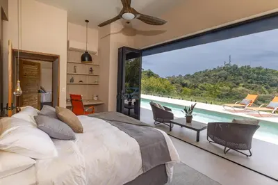 a bedroom with a bed and a large window at Villa Buddha Belly OceanMountain top views in Quepos