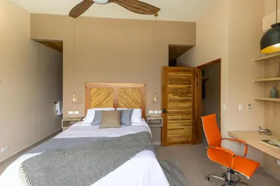 a bedroom with a bed and a desk and a chair at Villa Buddha Belly OceanMountain top views in Quepos