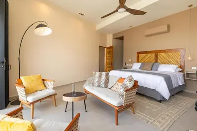 a bedroom with a bed and a couch and chairs at Villa Buddha Belly OceanMountain top views in Quepos