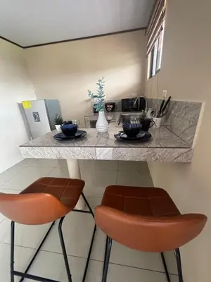 a kitchen with two bar stools and a counter at Hotel Nativo Arenal in Fortuna