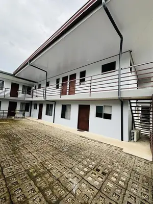 a large white building with a rug in front of it at Hotel Nativo Arenal in Fortuna