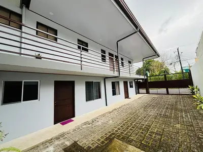 a large white building with a brick courtyard at Hotel Nativo Arenal in Fortuna