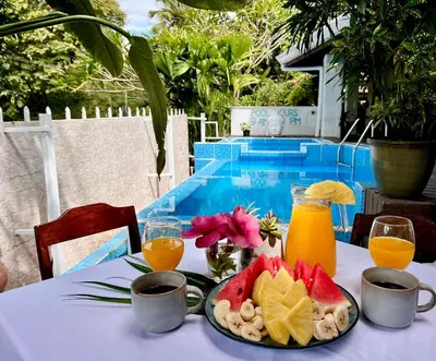 a table with a plate of fruit and orange juice at Kika Zaru Free MA Park Tour & Breakfast in Manuel Antonio
