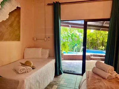 a bedroom with a bed with towels and a sliding glass door at Kika Zaru Free MA Park Tour & Breakfast in Manuel Antonio