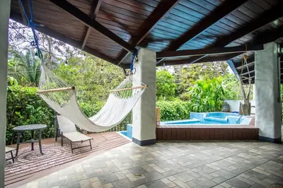 a patio with a hammock and a pool at Kika Zaru Free MA Park Tour & Breakfast in Manuel Antonio