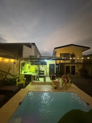 two people sitting around a swimming pool at night at Pelíkano Uvita in Uvita
