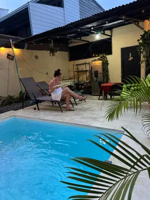 a woman sitting in a chair next to a swimming pool at Pelíkano Uvita in Uvita