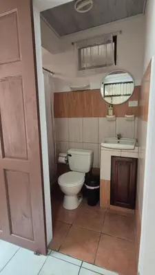 a bathroom with a toilet and a sink and a mirror at Velaz Guesthouse in Alajuela City