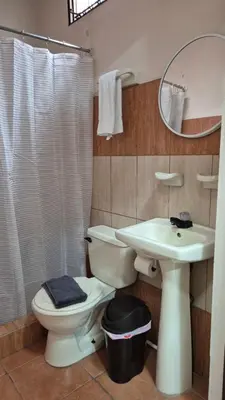 a bathroom with a toilet and a sink and a mirror at Velaz Guesthouse in Alajuela City