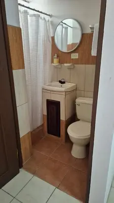 a bathroom with a toilet and a sink and a mirror at Velaz Guesthouse in Alajuela City