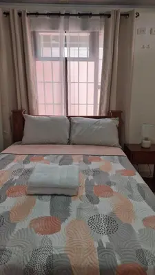 a bedroom with a bed with a large window at Velaz Guesthouse in Alajuela City