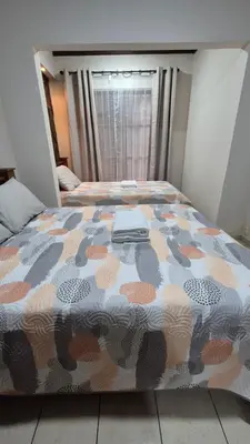 a bedroom with a bed with a comforter on it at Velaz Guesthouse in Alajuela City