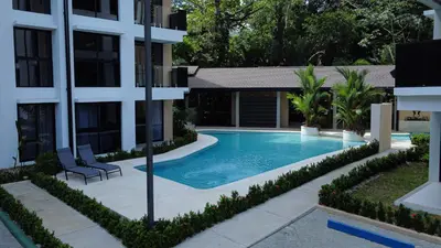 a swimming pool in front of a building at Bird & Surf 2BD Retreat Jungle Views Pool Gym in Jacó
