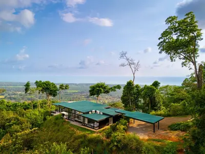 a house on a hill with a green roof at NEW Luxury! Panoramic views-Pool-Private-Gated in Portalón