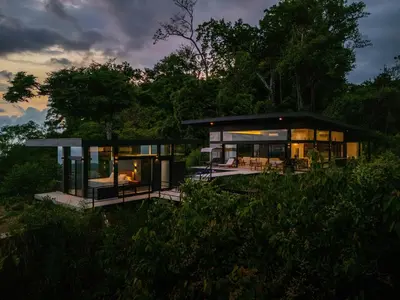 a modern house with glass doors and windows at night at NEW Luxury! Panoramic views-Pool-Private-Gated in Portalón