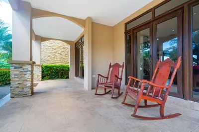 a group of red chairs sitting on a porch at 1hr SJO Airport-Ocean views-Gated Beachclub-Pool in Tarcoles