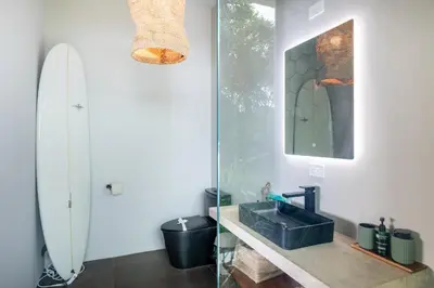 a bathroom with a sink and a surfboard on the wall at NEW! Modern-Luxury-3 suites-pool-Ojochal-100MBPS in Ojochal