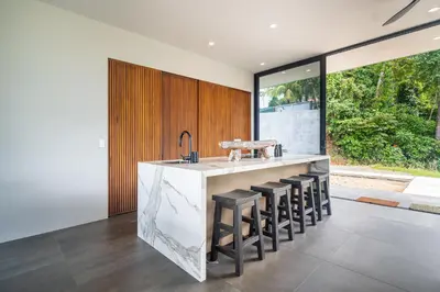 a kitchen with a sink and some stools at NEW! Modern-Luxury-3 suites-pool-Ojochal-100MBPS in Ojochal