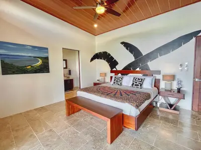 a bedroom with a bed with a painting on the wall at 3 Suites-Views-Great pool-Near Dominical-Luxury in Laguna