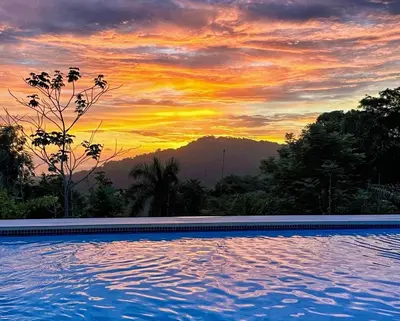 a swimming pool with a sunset in the background at 3 Suites-Views-Great pool-Near Dominical-Luxury in Laguna