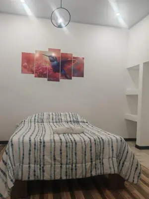 a bed in a room with three paintings on the wall at Happy Family in Quepos