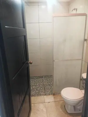 a bathroom with a toilet and a glass shower door at Happy Family in Quepos