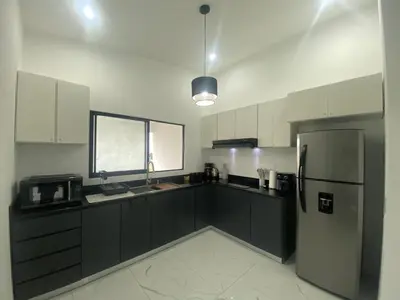 a kitchen with black cabinets and a refrigerator at El Chante cerca de playas, piscinas y vistas a la montaña in Herradura
