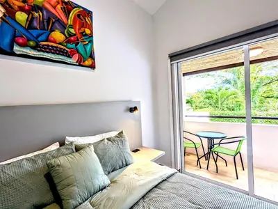 a bedroom with a bed and a table and a window at Upscale Tropical Retreat - 4BR in Gated Resort in Jacó