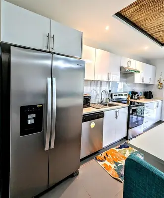 a stainless steel refrigerator in a kitchen with white cabinets at Upscale Tropical Retreat - 4BR in Gated Resort in Jacó