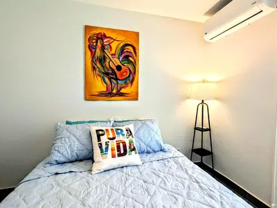 a bedroom with a bed and a painting on the wall at Upscale Tropical Retreat - 4BR in Gated Resort in Jacó