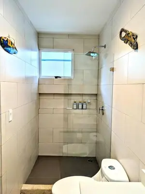 a bathroom with a shower with a toilet and a window at Upscale Tropical Retreat - 4BR in Gated Resort in Jacó