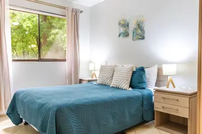 a bedroom with a blue bed and a window at Cozy Condo with Panoramic Hillside Views from Rooftop Terrace and Short Walk to Beach in Coco