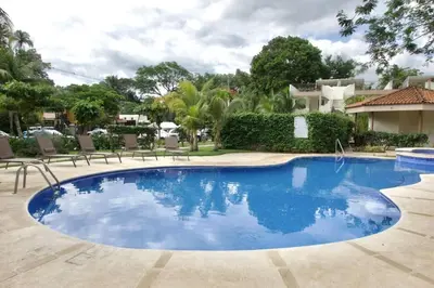 a large swimming pool with blue water in a yard at Cozy Condo with Panoramic Hillside Views from Rooftop Terrace and Short Walk to Beach in Coco