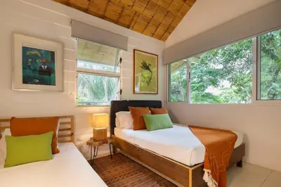 a bedroom with two beds and two windows at Art Bungalow Walking distance to the beach in Santa Teresa Beach