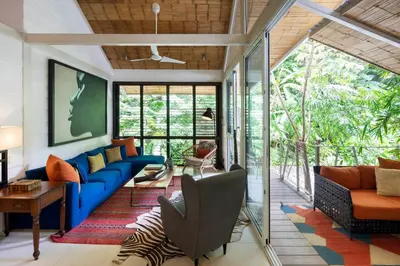 a living room with a blue couch and glass doors at Art Bungalow Walking distance to the beach in Santa Teresa Beach