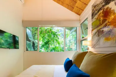 a bedroom with a bed and a large window at Art Bungalow Walking distance to the beach in Santa Teresa Beach