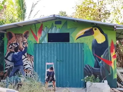 a mural of a tiger and a child in front of a building at Java blue banana in Santa Cruz