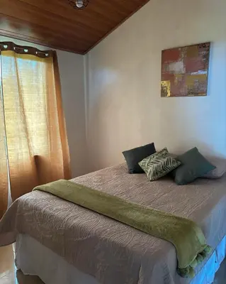 a bedroom with a bed with green sheets and a window at Monteverde Sunset House in Cebadilla